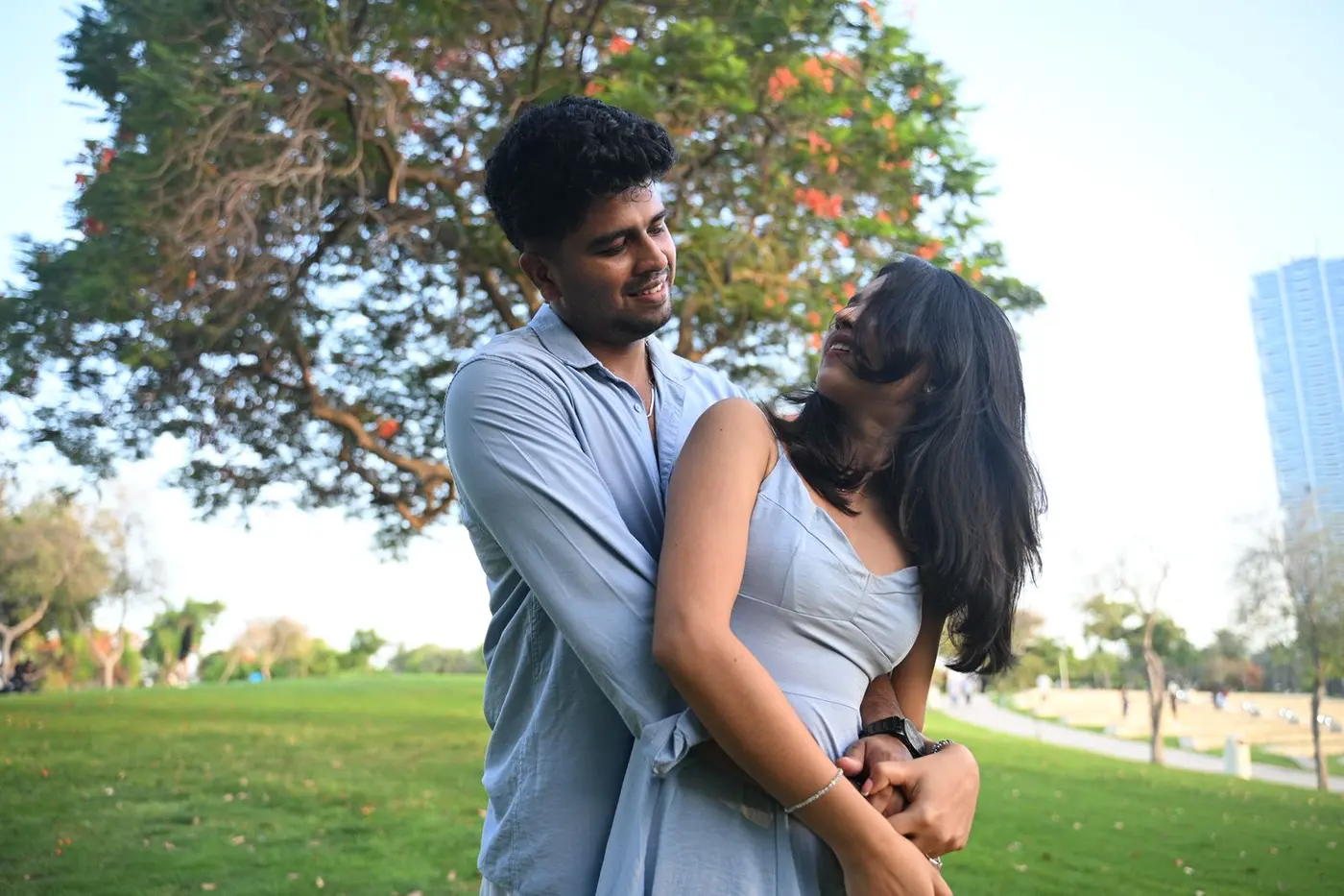 Unni holding Hridya close under a tree in the park